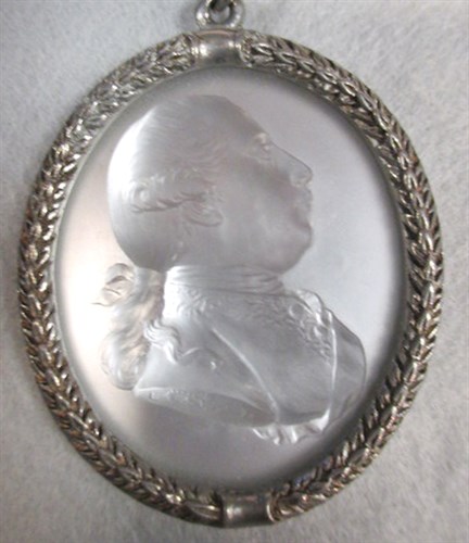 Lot 278 - A 1761 satin glass relief profile of George III in later silver frame with neck chain