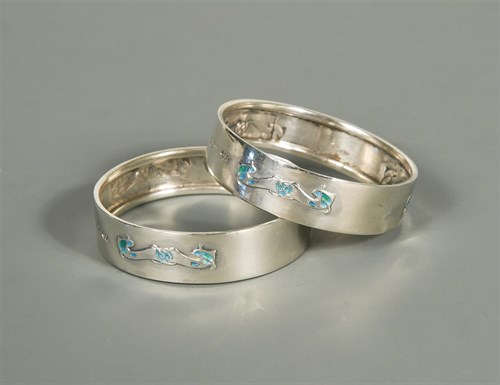 Lot 110 - Liberty & Co., a pair of silver and enamel napkin rings
