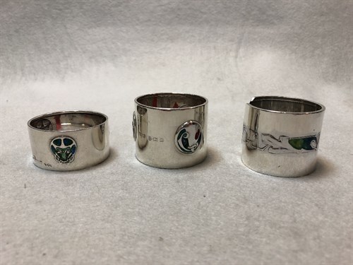 Lot 113 - Liberty & Co., two silver and enamel napkin rings and another by William H. Haseler