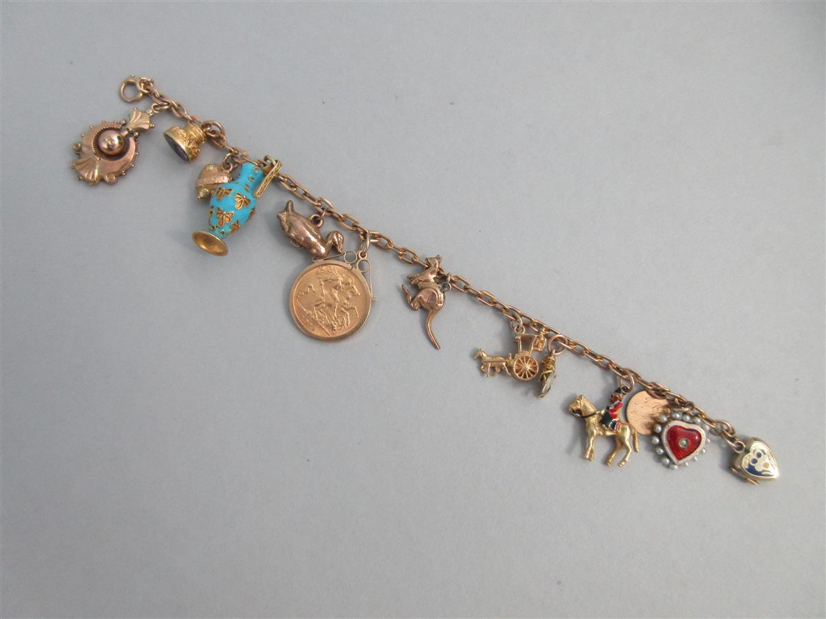 Lot 335 - A charm bracelet with two antique enamelled heart lockets and a half sovereign amongst other charms
