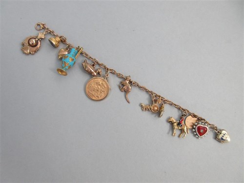 Lot 335 - A charm bracelet with two antique enamelled heart lockets and a half sovereign amongst other charms