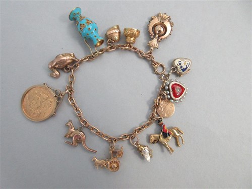 Lot 335 - A charm bracelet with two antique enamelled heart lockets and a half sovereign amongst other charms