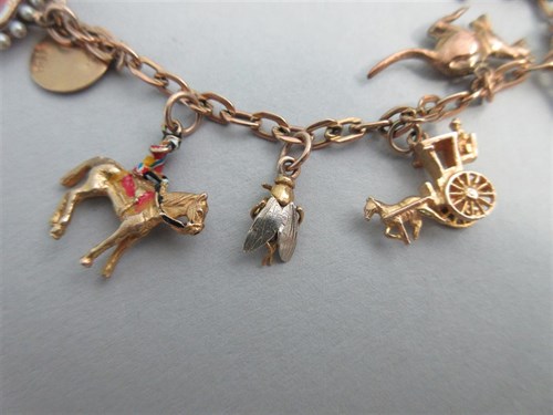 Lot 335 - A charm bracelet with two antique enamelled heart lockets and a half sovereign amongst other charms