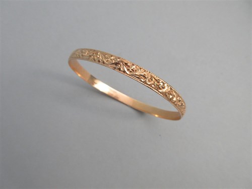 Lot 343 - A carved slave bangle of yellow metal that tests for 18ct gold