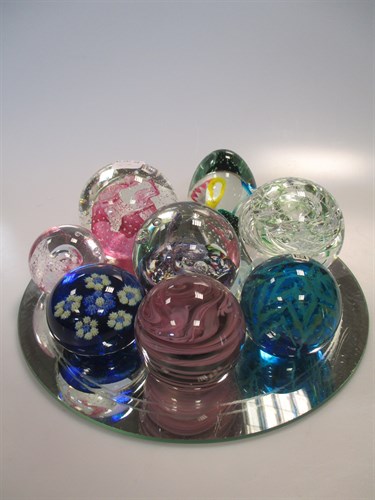 Lot 17 - Eight Mdina and other glass paperweights on a...