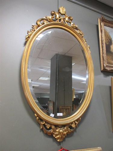 Lot 439 - An oval gilt framed wall mirror with shell and...