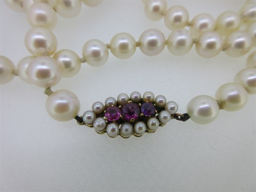Lot 384 - An opera length cultured pearl necklace with a ruby and seed pearl clasp, together with a pair of pearl earstuds