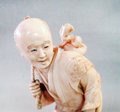 Lot 182 - An ivory okinomo, the figure carrying a large parsnip, Meiji period