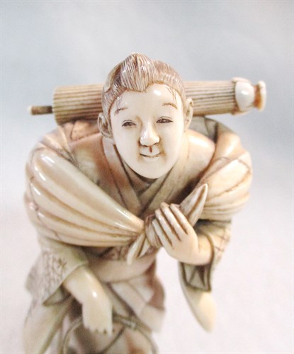 Lot 132 - An ivory okimono of a man with a fish basket,...