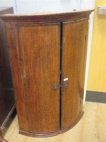 Lot 515 - A George III oak bow front corner cupboard