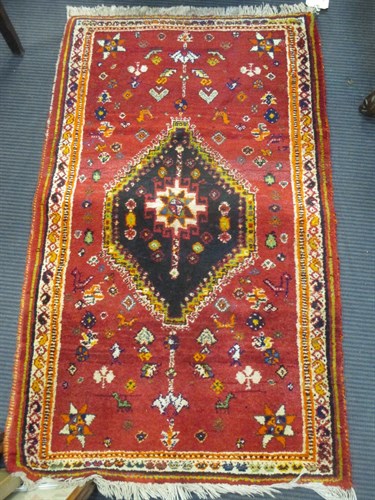 Lot 386 - A red ground rug with single medalion together...