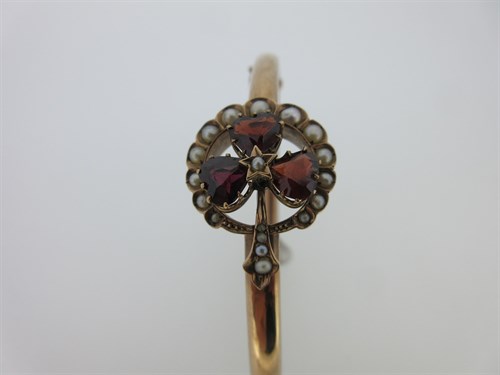 Lot 74 - A garnet and seed pearl shamrock bangle and a garnet set gold heart pendant