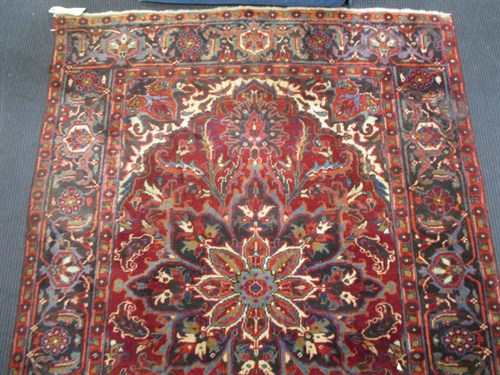 Lot 547 - A red ground rug with central floral design,...