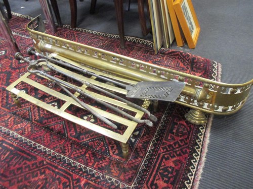 Lot 493 - A brass fender, a footman, and three fire irons