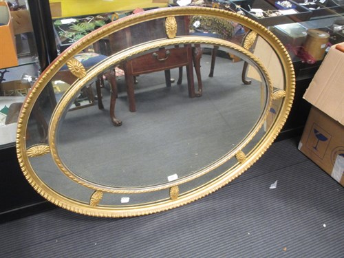 Lot 644 - An oval gilt wall mirror, c.1900, in Regency...