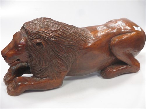 Lot 16 - A carved and stained pine model of a recumbent...