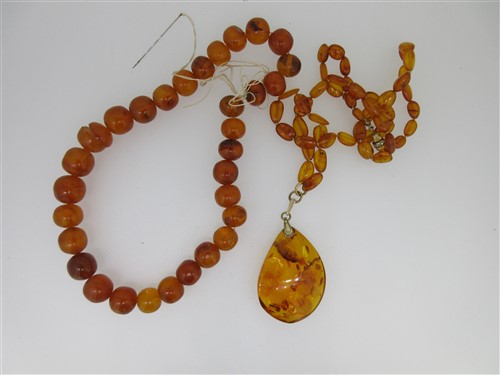 Lot 21 - A Russian amber pendant on necklace together with a loose string of vintage amber beads