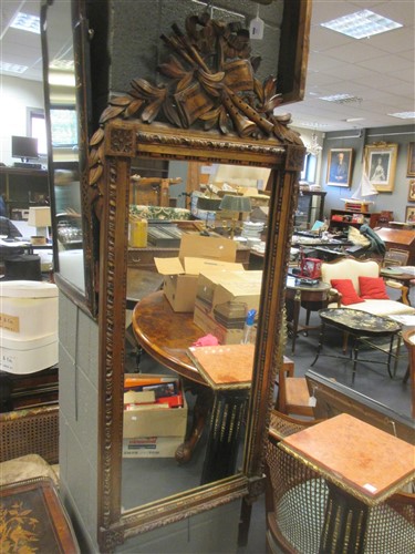 Lot 402 - A large gilt framed wall mirror, with trophy...