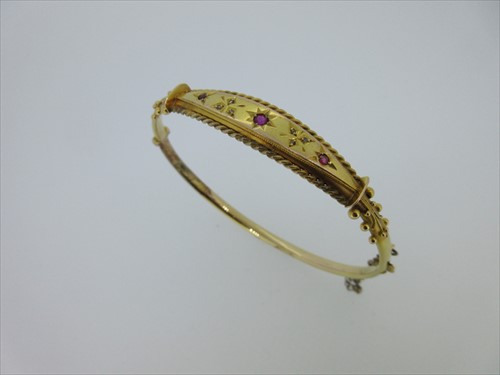 Lot 136 - An antique hinged bangle set with small rubies and diamonds
