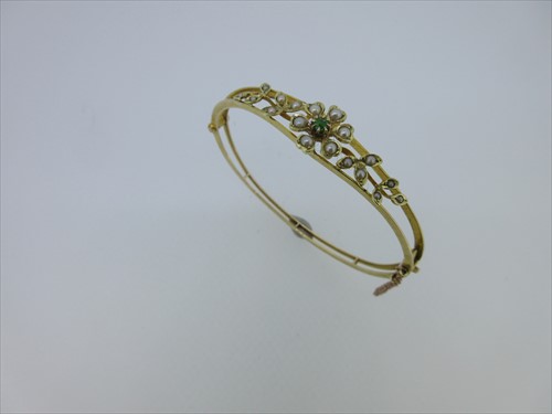 Lot 139 - An Edwardian hinged bangle set with seed pearls and a demantoid garnet