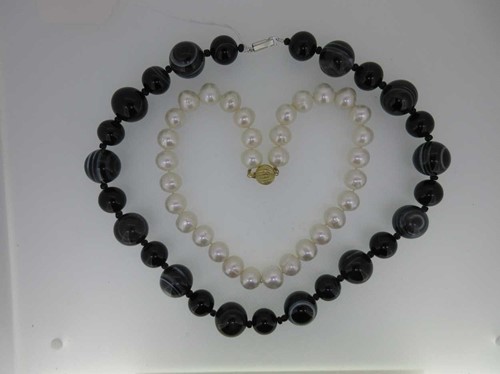 Lot 34 - A row of uniform pearls together with a banded agate necklace