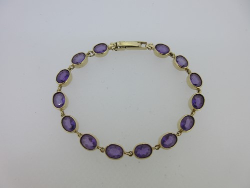 Lot 221 - An amethyst line bracelet in hallmarked gold
