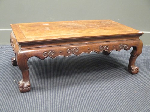 Lot 486 - A Chinese hardwood low table on claw and ball...