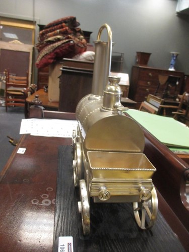 Lot 106 - A silver coloured novelty locomotive shape urn...