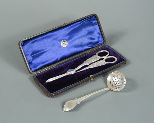 Lot 548 - A cased pair of Victorian silver grape scissors and a sifting spoon, by George Unite