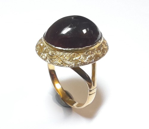 Lot 46 - A dress ring set with a cabochon garnet