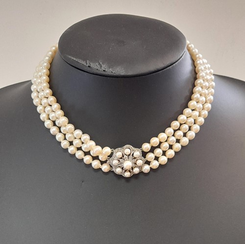 Lot 73 - A three row pearl collar with a diamond set clasp