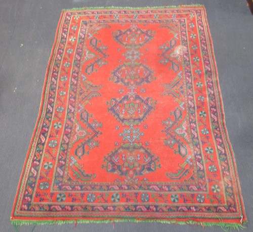 Lot 899 - a red ground rug with four central medallions,...