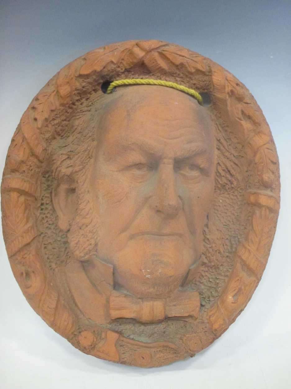 Lot 46 - A terracotta oval wall plaque sculpted with...