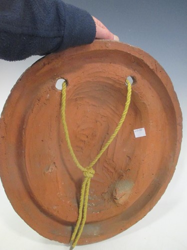 Lot 46 - A terracotta oval wall plaque sculpted with...