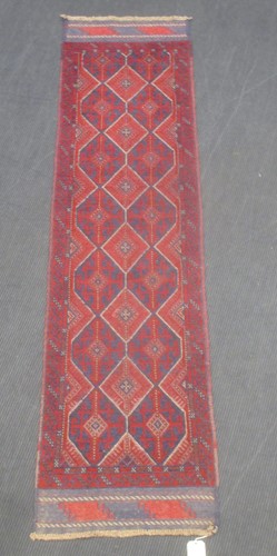 Lot 733 - A red ground runner decorated with six...