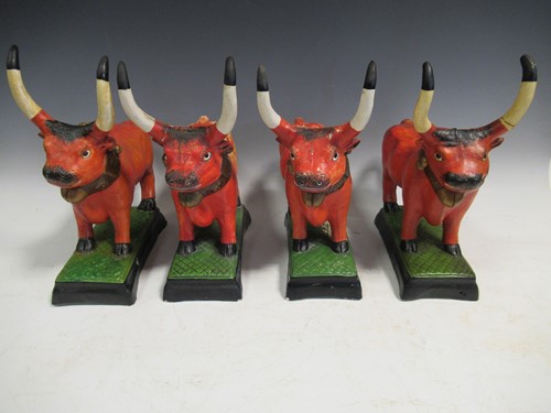 Lot 37 - A set of pottery bulls, painted in orange on...