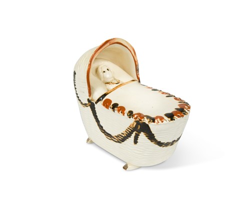 Lot 199 - A Bovey Pottery creamware cradle with a sleeping child, circa 1790