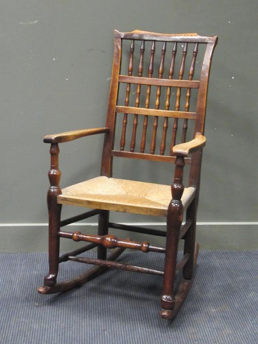 Lot 550 - A rush seated stick back rocking chair 108cm high