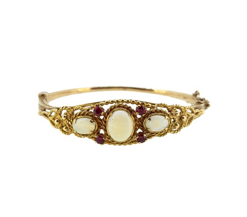 Lot 75 - A modern opal and ruby hinged bangle