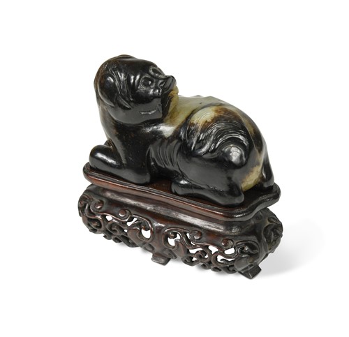 Lot 147 - A Chinese celadon and russet jade recumbent fo-dog, Qing Dynasty