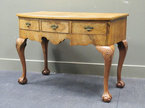 Lot 570 - A walnut bow front dressing table with glass...