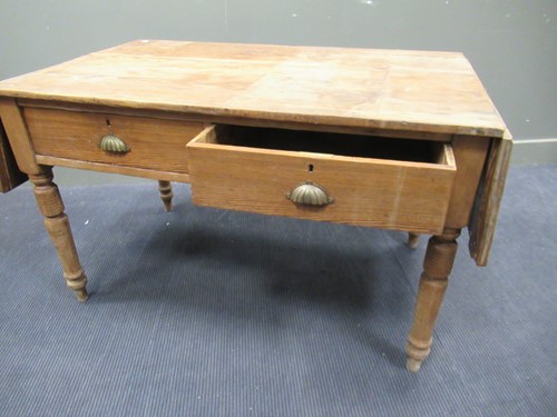Lot 572 - A pine drop leaf table with two drawers on...