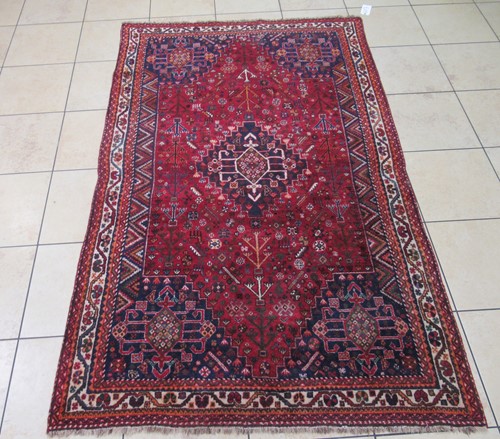 Lot 603 - A Quashqui red ground rug with central...