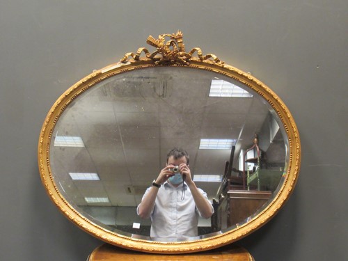 Lot 471 - An oval gilt wall mirror surmounted by...