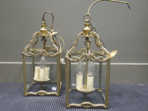 Lot 668 - A pair of brass three light hall lanterns, the...
