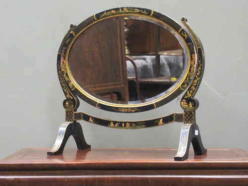 Lot 671 - A Japanned oval swing mirror with bevelled...