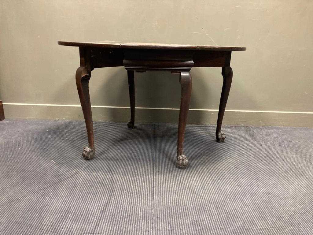 Lot 523 - An oval drop leaf table with carved lion-paw...