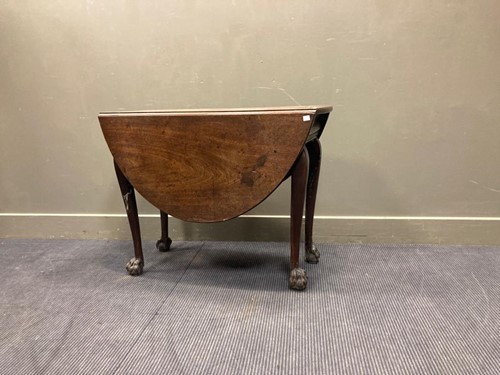 Lot 523 - An oval drop leaf table with carved lion-paw...