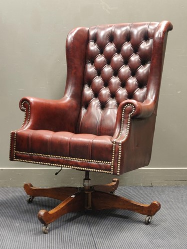 Lot 533 - A modern leather wingback armchair on a swivel...