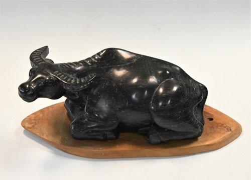 Lot 159 - A Chinese black striated stone model of a recumbent water buffalo, late Qing circa 1900